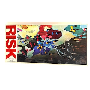 May include: A vintage Risk board game. The game board features a world map with territories marked by colored pieces. The word "RISK" is in large red letters on the left side. A black cannon is in the lower right corner.