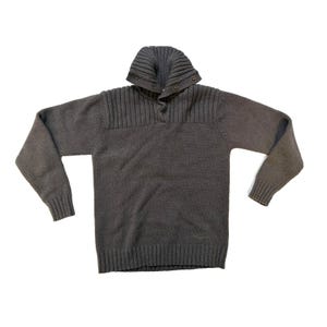 May include: A grey knitted sweater with a ribbed collar and button closure. The sweater features a high, folded collar and ribbed detailing on the shoulders. The long sleeves end in ribbed cuffs. The bottom hem is also ribbed.