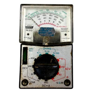 May include: A vintage analog multimeter with a white faceplate, black casing, and a central rotary dial. The display features green and red scales for OHMS, DCV, and ACV measurements. Text includes Universal Enterprises M20 and Portland Oregon.