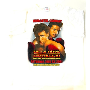May include: White t-shirt featuring a graphic of two boxers with red gloves. The text reads "IMMORTAL COMBAT" above "DE LA HOYA vs CASTILLEJO" and event details: "SATURDAY, JUNE 23, 2001 LIVE AT THE MGM GRAND LAS VEGAS."