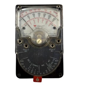 May include: A vintage Triplett Model 310 analog multimeter with a clear plastic cover, a white scale face featuring red and black markings, and a black base. The device includes two input jacks labeled COM and V-O-M, with 1200V DC and AC markings.