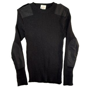 May include: A black long-sleeve sweater featuring a ribbed knit texture, a crew neckline, and solid black fabric patches on the shoulders and elbows. A white rectangular label is visible on the inside of the collar at the back of the neck.