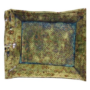 Puede incluir: Una fuente rectangular de cerámica con un patrón texturizado en forma de rejilla. La fuente presenta una combinación de colores verde y marrón con un borde azul. Los bordes de la fuente son ligeramente irregulares.