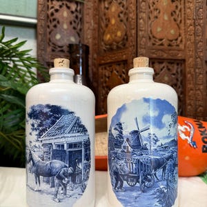 May include: A set of three ceramic canisters with lids, featuring a blue and white floral pattern. The canisters vary in size, with the largest measuring approximately 8 inches in height.