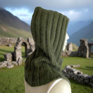 May include: Olive green knitted hood with a ribbed texture. The hood is designed to cover the head and neck, offering warmth and protection. The knitted hood is a versatile accessory for cooler weather.