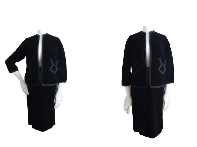 May include: A black velvet skirt suit with a jacket featuring a geometric design in a contrasting dark grey trim.