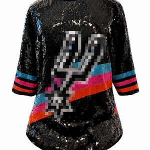 May include: A black sequined shirt featuring a pixelated silver spur logo in the center. The sleeves have horizontal stripes in light blue, pink, and orange. The garment has a round neckline and three-quarter length sleeves covered in black sequins.
