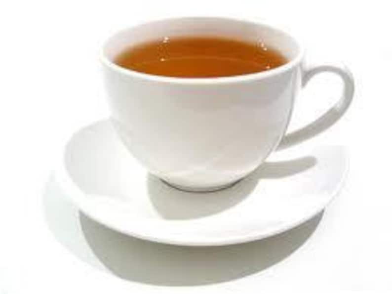 May include: A white ceramic teacup and saucer with a light brown tea inside.