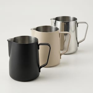 May include: A trio of ceramic mugs with a speckled, matte finish in cream, light grey, and dark grey. Each mug features a simple, minimalist design, ideal for tea or coffee.