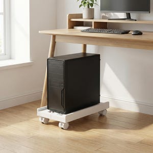 May include: A black computer tower on a white rolling cart, positioned under a wooden desk. The desk has a monitor, keyboard, and mouse. A small potted plant sits on the desk's shelf. The room has a window and wooden flooring.
