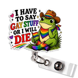 May include: A badge reel featuring a green frog wearing a brown cowboy hat with a rainbow band, a rainbow bandana, and rainbow cowboy boots. The frog holds a rainbow flag. Text reads: I HAVE TO SAY GAY STUFF OR I WILL DIE. A rainbow arc is below.