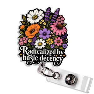 May include: A badge reel featuring a colourful floral illustration with white daisies, orange poppies, purple lavender, and pink coneflowers. The text "Radicalized by basic decency" is printed in a white script font at the bottom of the design.