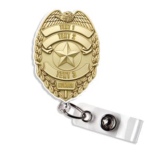 May include: A gold-toned badge reel featuring an eagle emblem at the top, a central five-pointed star, and three horizontal banners with the text "TEXT 1", "TEXT 2", and "TEXT 3", plus a bottom banner labeled "NUMBER" attached to a clear strap.
