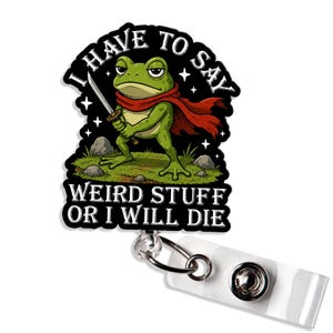 May include: A badge reel featuring a green frog wearing a red cape and holding a sword. The text reads I HAVE TO SAY WEIRD STUFF OR I WILL DIE. The design is set against a black background with white stars, attached to a clear plastic strap.