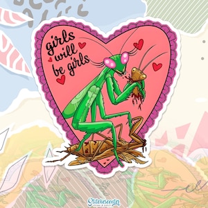 May include: A sticker with a pink heart shape and a scalloped edge. The sticker features a green praying mantis eating a smaller insect, with the text "girls will be girls" and small red hearts. The sticker has the text "StitchesCenter" at the bottom.