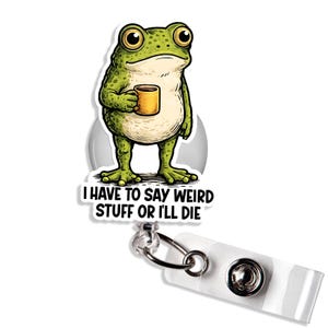 May include: A green frog cartoon holding a yellow mug, with the text "I HAVE TO SAY WEIRD STUFF OR I'LL DIE" on a white badge reel. The reel has a clear plastic strap and a metal clip.