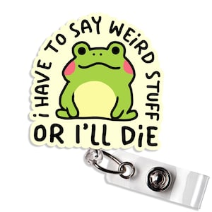 May include: A badge reel with a cartoon frog illustration. The frog is green with pink cheeks and a yellow belly. Text on the badge reads "I HAVE TO SAY WEIRD STUFF OR I'LL DIE."