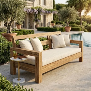 Könnte beinhalten: Ein hölzernes Outdoor-Sofa mit einem hellfarbenen Kissen und drei passenden Kissen. Das Sofa steht neben einem kleinen runden Beistelltisch mit Marmorplatte und einem Getränk. Der Hintergrund ist eine Terrasse mit Pool und einem Steingebäude.