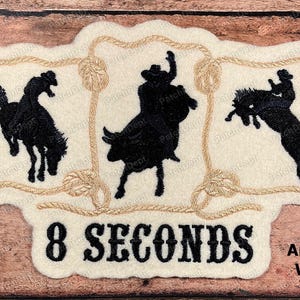 May include: Embroidered patch featuring rodeo scenes with a horse, bull, and rider in black thread on an antique white background. The patch includes the text "8 SECONDS" in bold black letters, and "Antique White" text.