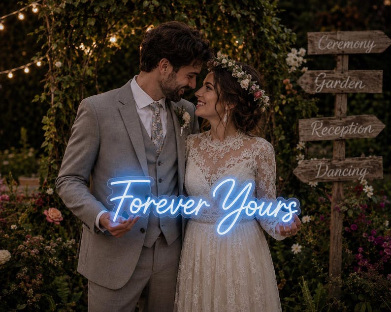 May include: A bright blue neon sign featuring the cursive text Forever Yours. The sign is held by two individuals, one wearing a grey suit with a vest and tie, and the other wearing a white lace long-sleeve dress with a floral headpiece.