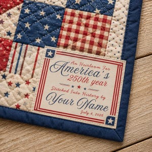 Puede incluir: Una pieza de tela acolchada con un patrón de estrellas y cuadros vichy en rojo, blanco y azul, con una etiqueta central que dice: An Heirloom For America's 250th year Stitched Into History by Your Name July 4, 2026, enmarcada por un borde azul.