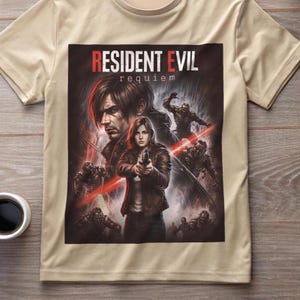 May include: A tan t-shirt featuring a graphic from the video game "Resident Evil: Requiem." The graphic depicts characters from the game, including a woman holding a gun, and the game's title in red letters.