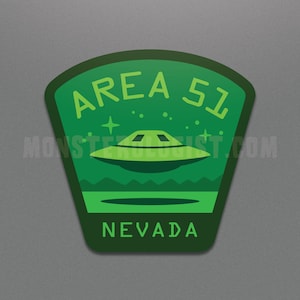Könnte beinhalten: Grüner und weißer Area 51 Patch mit einer fliegenden Untertasse, Sternen und dem Text "AREA 51" und "NEVADA".