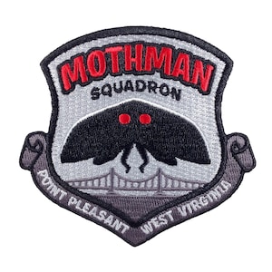 Op de afbeelding: Een grijs geborduurd patch met de tekst "Mothman Squadron" in rood. De patch heeft een zwarte mot met rode ogen en een grijze brug eronder. De tekst "Point Pleasant West Virginia" staat in een gebogen boog rond de onderkant van de patch.