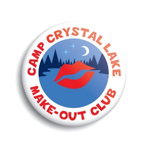 May include: A white button with red text that reads "Camp Crystal Lake Make-Out Club". The button has a blue background with a red lip print, a crescent moon, and stars.
