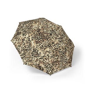 May include: An open umbrella with a tan and black leopard print pattern. The umbrella is a neutral color and has a classic design. The umbrella is a stylish accessory for rain or shine.