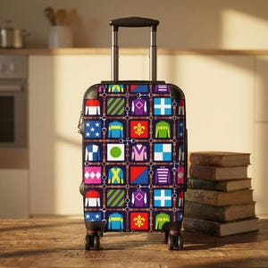 Pode incluir: Uma mala de rodinhas com um padrão colorido de sedas de jóquei. O design apresenta quadrados de várias cores e padrões, incluindo estrelas, listras e cruzes, conectados por tiras de couro marrom. A mala tem uma alça e rodas pretas.