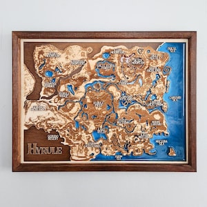 Könnte beinhalten: Eine gerahmte Holzkarte von Hyrule mit lasergeschnittenem Gelände und blauen Harz-Wasserflächen. Die Karte enthält geografische Bezeichnungen wie Berge, Wälder und Meere, in einem dunkelbraunen Holzrahmen.