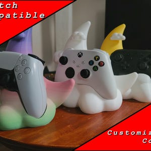 May include: Gaming controller stands in the shape of clouds, each holding a different controller. The stands are white with colorful accents, and the controllers are white and black. Text on the image reads "Switch Compatible" and "Customizable Colors."