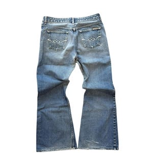 Peut inclure: Jean bleu clair avec une coupe évasée. Le jean a deux poches arrière avec des coutures décoratives et une conception classique à cinq poches. Le jean est fait d'un matériau en denim durable et comporte une fermeture à bouton et à glissière.