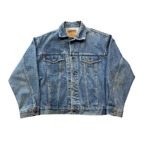 May include: A light blue denim jacket with a classic design. The jacket has a button-up front, two chest pockets, and two side pockets. The denim has a faded, worn appearance.