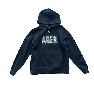 May include: A navy blue hoodie with a drawstring hood and a kangaroo pocket. The word "ADER" is printed across the chest in a white camouflage pattern. The long-sleeved sweatshirt is made of a soft material.