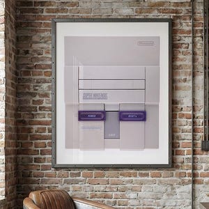 May include: A framed wall art print featuring a light gray Super Nintendo game console. The console graphic displays the Nintendo logo, the Super Nintendo text, and two prominent purple buttons labeled Power and Reset, centered on a white background.