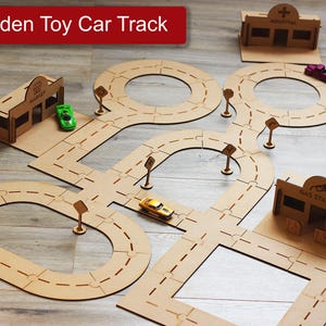 Puede incluir: Juego de pistas de coches de juguete de madera con un mercado, un hospital y una gasolinera. La pista es de madera marrón claro e incluye señales de tráfico y coches de juguete. El texto "Wooden Toy Car Track" está en la parte superior.