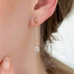 Minimalistische, lange Ohrringe in Tropfenform aus Gold mit zarten, klaren Steinen. Der tropfenförmige Schliff und das geradlinige Design machen diese Ohrringe perfekt für den Alltag, das Büro oder als Geschenk für Ihre Freundin. Handgefertigt von einem japanischen Kunsthandwerker.