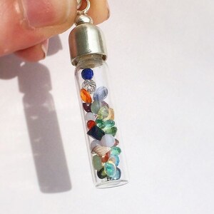 May include: A silver charm necklace with a glass vial filled with colorful gemstones and seashells.