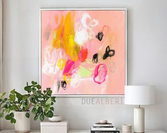 Op de afbeelding: Een vierkant abstract schilderij in een witte lijst met een zachte perzikkleurige achtergrond, gelaagde penseelstreken in felgeel, roze, wit en limoengroen, geaccentueerd door gedurfde, zwarte krabbellijnen en de tekst DUEALBERI.