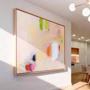 May include: A large rectangular abstract painting in a light wood frame featuring a pale cream background with accents of bright lime green, vibrant orange, hot pink, and white. The text DUE ALBERI is printed in small red letters below the artwork.