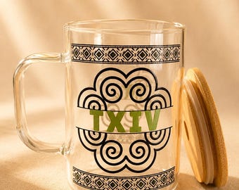 May include: A clear glass mug with a handle, featuring a black geometric border pattern at the top and bottom. In the center, a black spiral design surrounds the green text TXIV. A round, light-colored wooden lid with a silicone seal sits beside it.