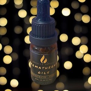 May include: A small brown aromatherapy oil bottle with a black dropper and cap. The label reads "Invicta Aromas Aromatherapy Oils Concentrated - Premium" with a flame logo. The bottle contains 10ml (0.34 fl oz).