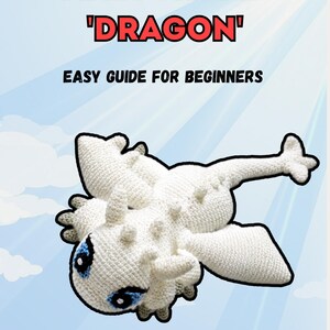May include: A white crocheted amigurumi dragon with blue eyes and small spikes along its back. The text on the image reads AMIGURUMI 'DRAGON' EASY GUIDE FOR BEGINNERS. The dragon is shown from a top-down perspective against a light blue sky.