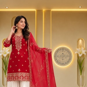 Puede incluir: Una túnica roja hasta la rodilla con bordados dorados en el cuello, puños y dobladillo, combinada con pantalones blancos anchos con un dobladillo bordado en oro. Un dupatta rojo transparente a juego con bordados florales dorados.