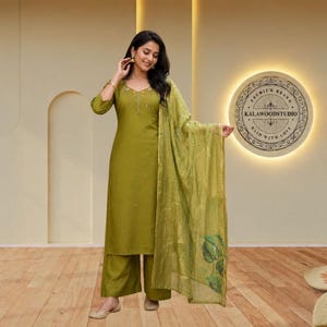 May include: An olive green three-piece ensemble consisting of a straight-cut kurta with three-quarter sleeves, wide-leg trousers, and a matching lightweight dupatta featuring a subtle leaf print pattern along the lower edge and a V-neckline.