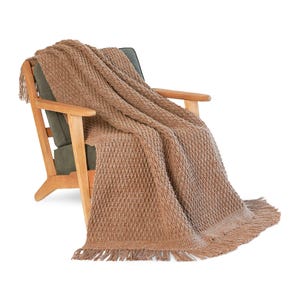 May include: A brown knitted throw blanket with a diamond pattern and fringe detail is draped over a wooden armchair with a green cushion. The blanket is a warm, neutral color, perfect for adding texture and comfort to a living space.
