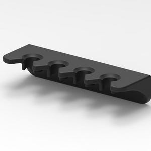May include: A matte black wall-mounted organizer rack featuring four circular cutouts designed to hold cylindrical items. The rack has a rectangular back plate and a protruding front edge with evenly spaced openings for secure storage.