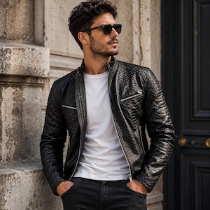 May include: Black leather jacket with a textured pattern, a zippered chest pocket, and a stand-up collar. The jacket is paired with a white t-shirt and black jeans. The person is also wearing black sunglasses.